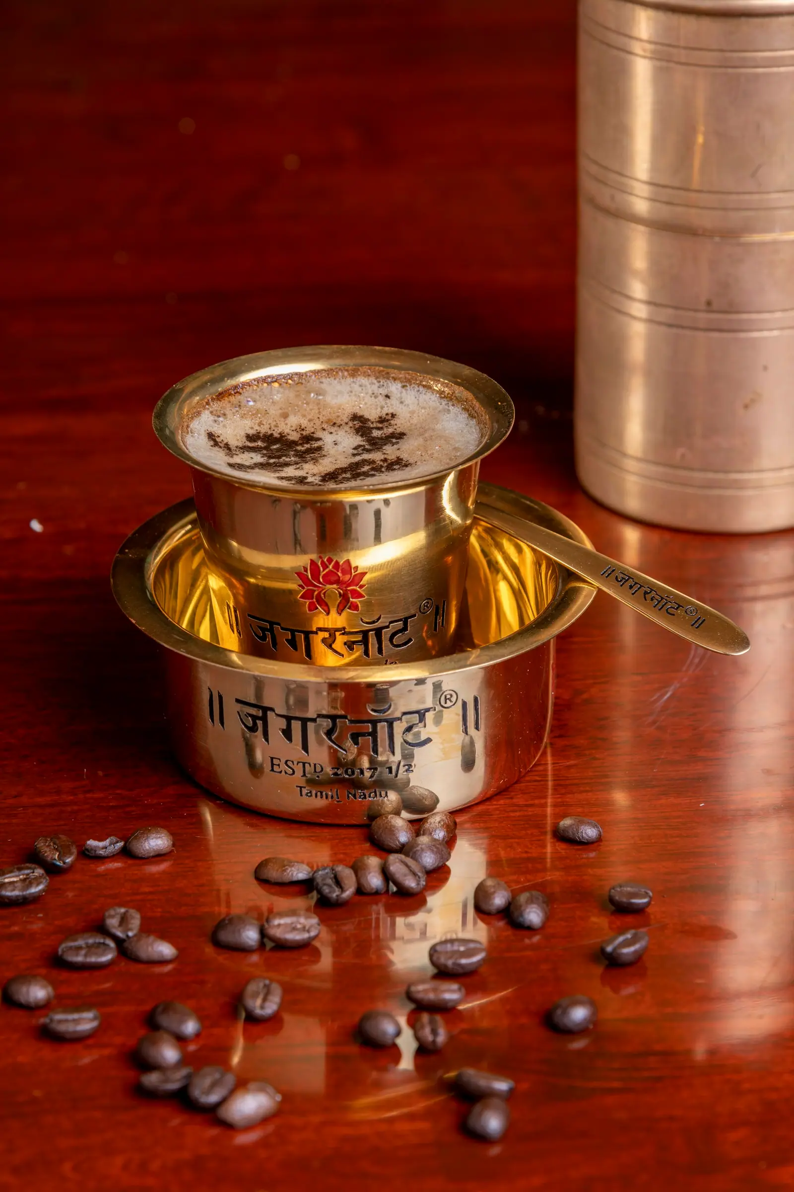 South Indian filter coffee set with a brass filter and coffee beans